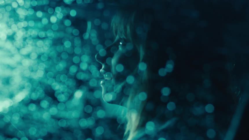 A closeup of a woman sitting in the drivers seat as heavy rain pours outside at night