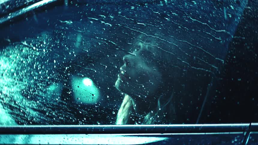 Woman sitting in her car during a storm watching the rain pound on her car