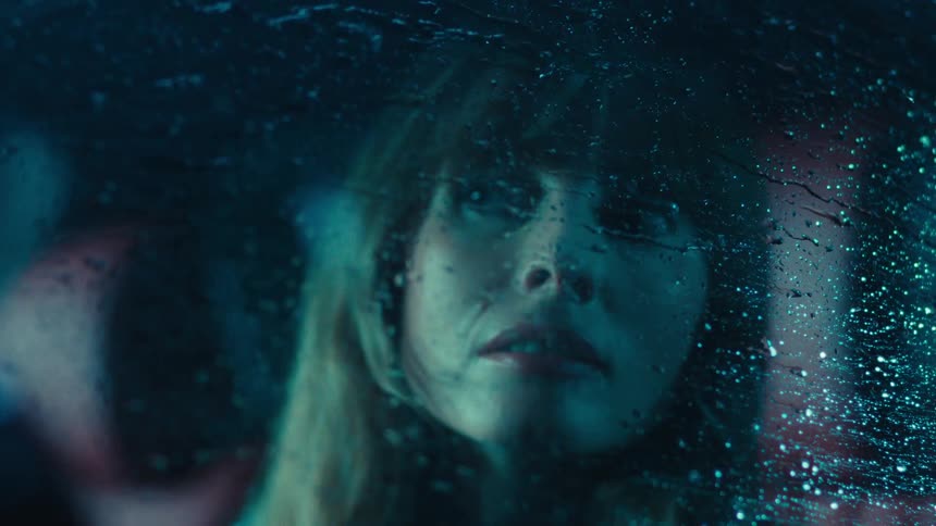 Woman inside a car watching the rain running down the window