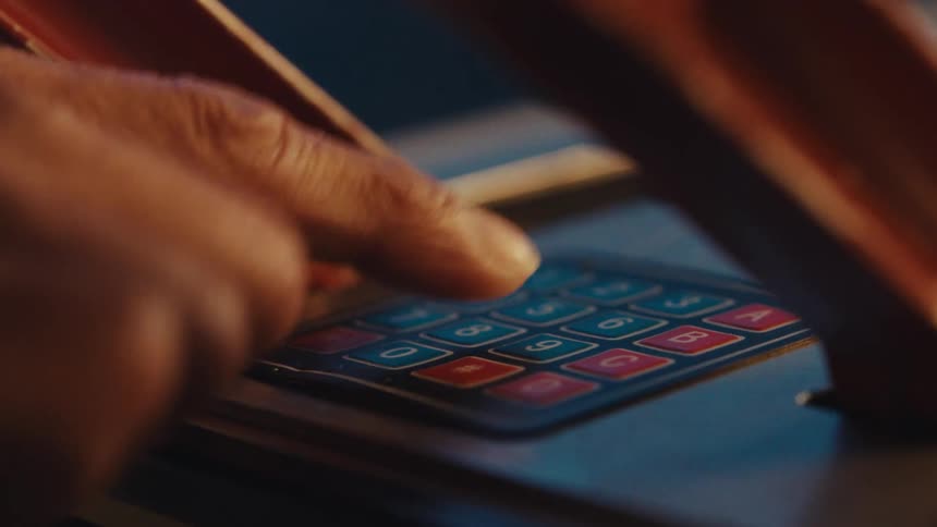 A finger presses a button on a numeric keypad with red and blue keys