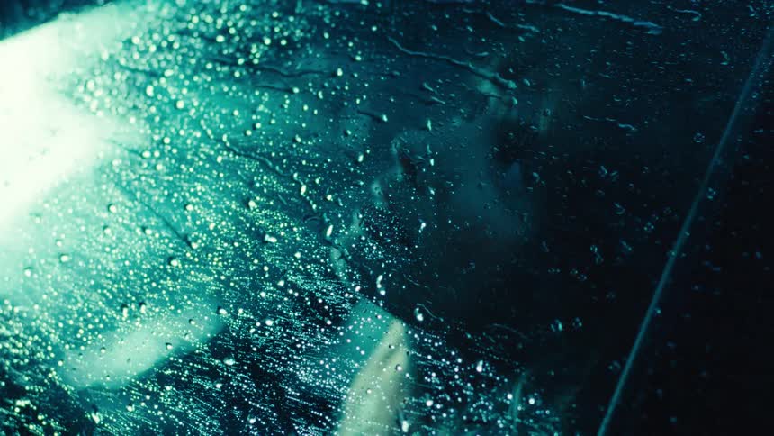 Woman inside a vehicle on a rainy day at night