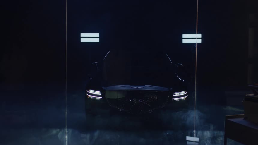 Scientist in white lab coat watching vehicle lights turn on inside a studio