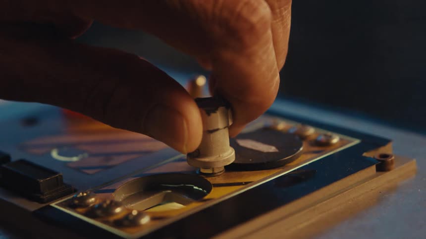 A person turns a wooden knob on a device