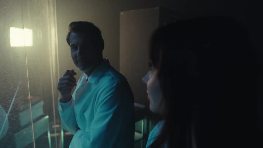 Twowhite coated professionals smile and exchange glances during a task at work