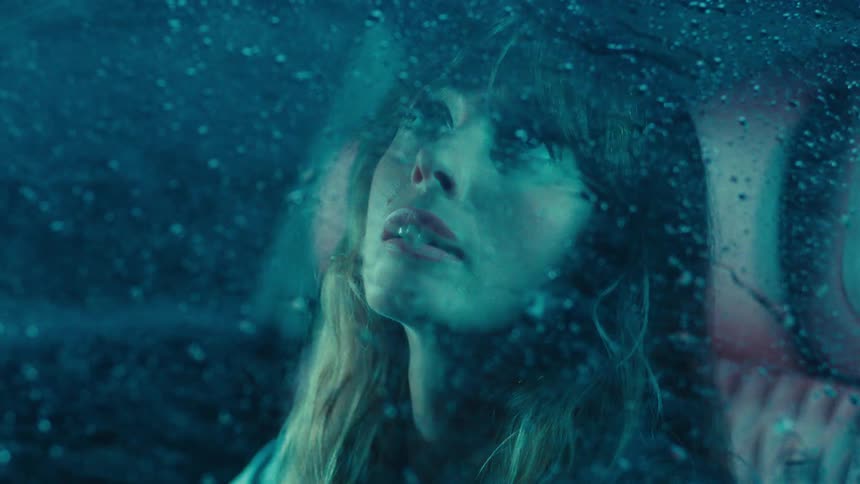 Woman sitting in her car at night watching heavy rain fall during a storm