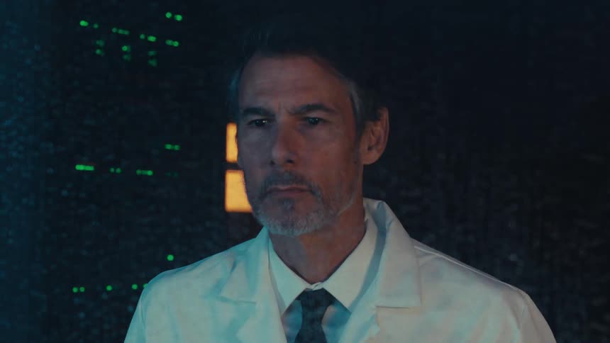 Male engineer in white coat and tie looking through a window