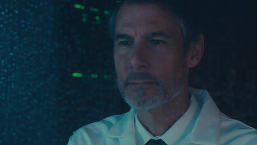 Man in lab coat and tie looking through a wet window