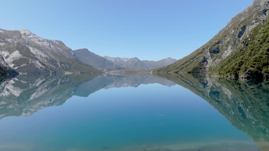 Landscape of a blue lake reflecting the sky and the mountains on the shore