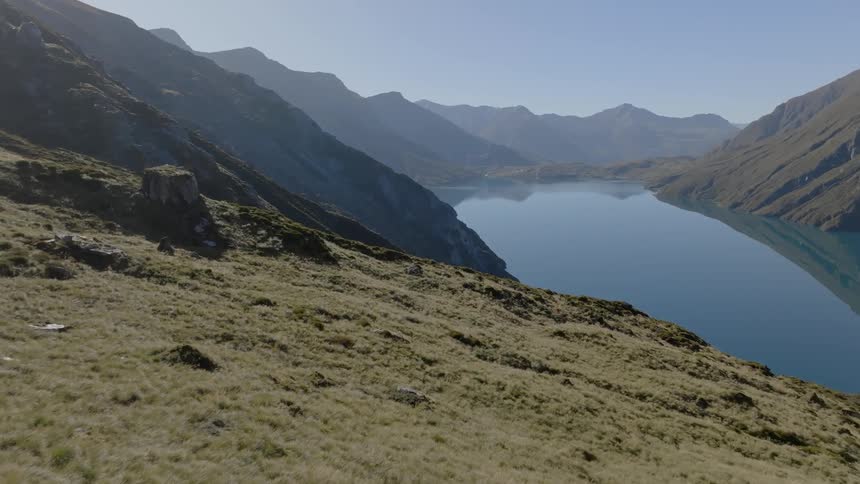 The haze of summer heat hangs over a mountain range with a lake