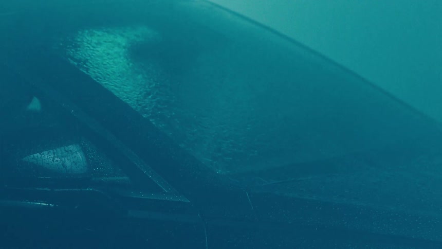 Rain falling on the windshield of a parked car