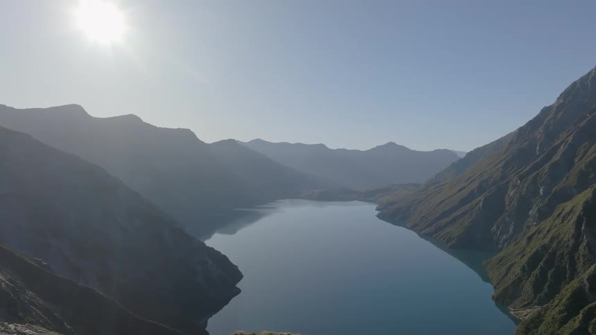 A tranquil mountain range encircling a pristine blue lake under a bright cloudless sky