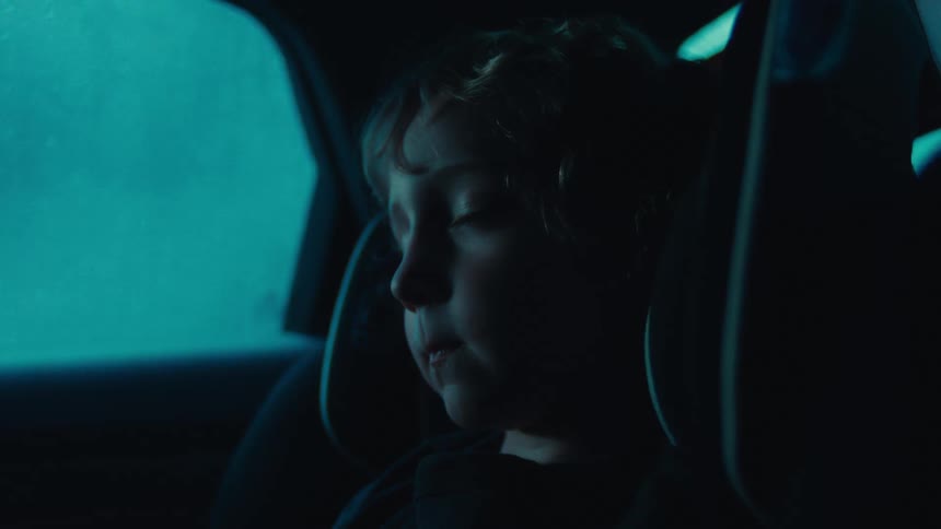 Little boy sleeping in a car seat in the back seat
