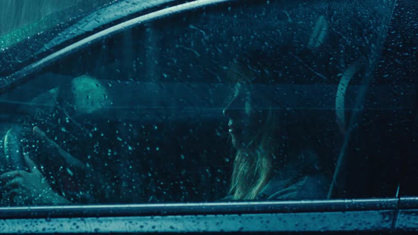 Its raining out while a woman is sitting in her parked car