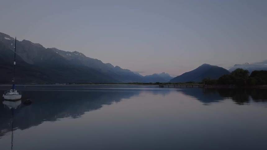 Calm lake at dawn with mountains around