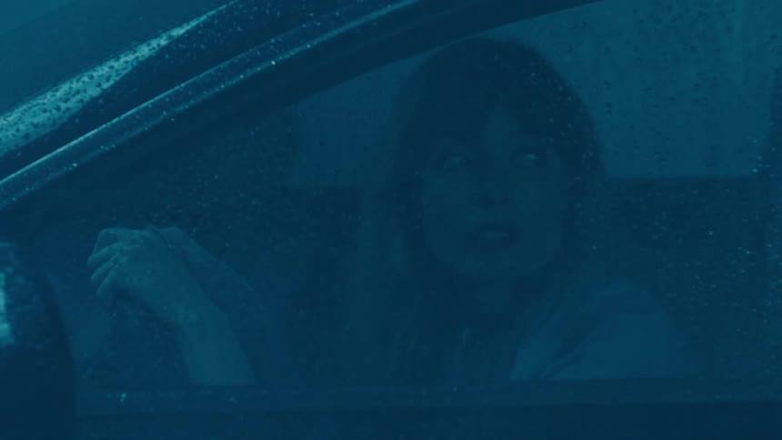 Woman scared while behind the wheel of a car on a rainy day
