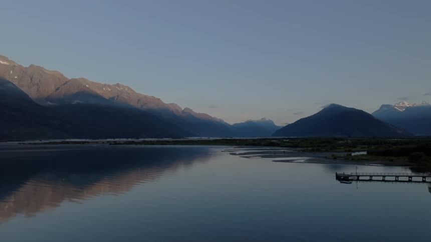 Panorama still at dawn of a calm lake and mountains around