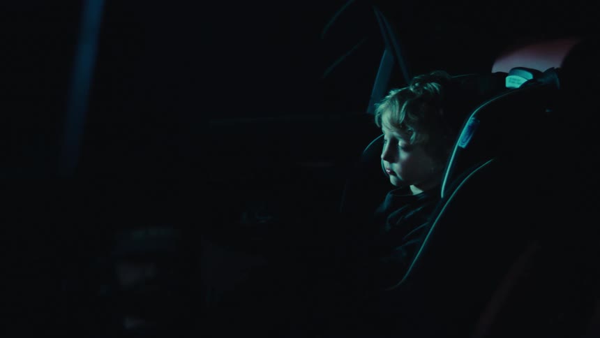 Mother and daughter inside the car with the little girl sitting sleeping in the back seat