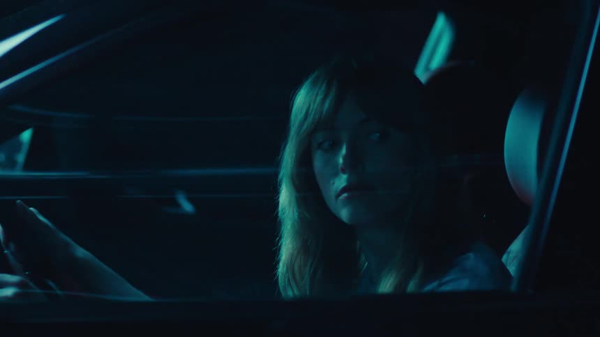 Woman inside a car looking to the side intently