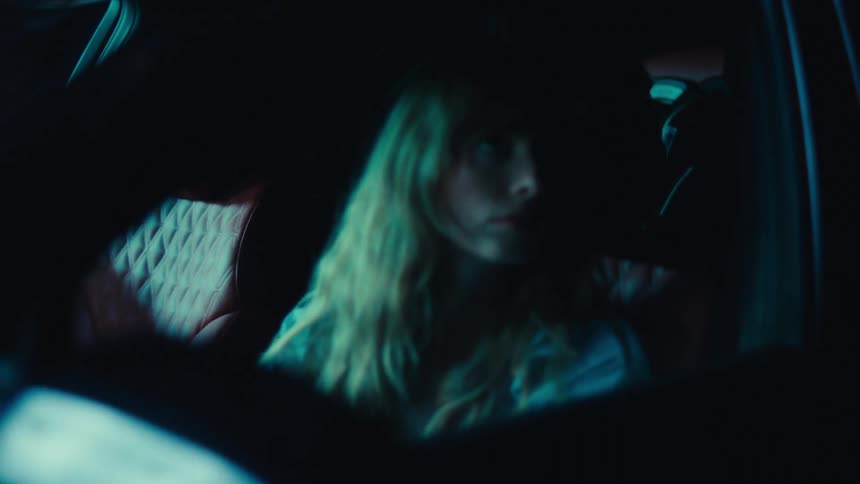A mother drives at night glancing around while her son sits in the backseat of the car