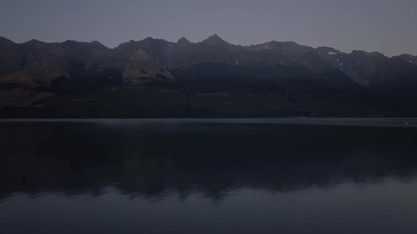 A lake in the mountains barely has ripples on the surface