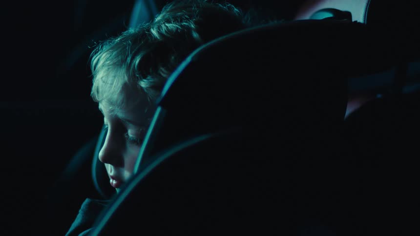 A child is resting in the backseat of the car