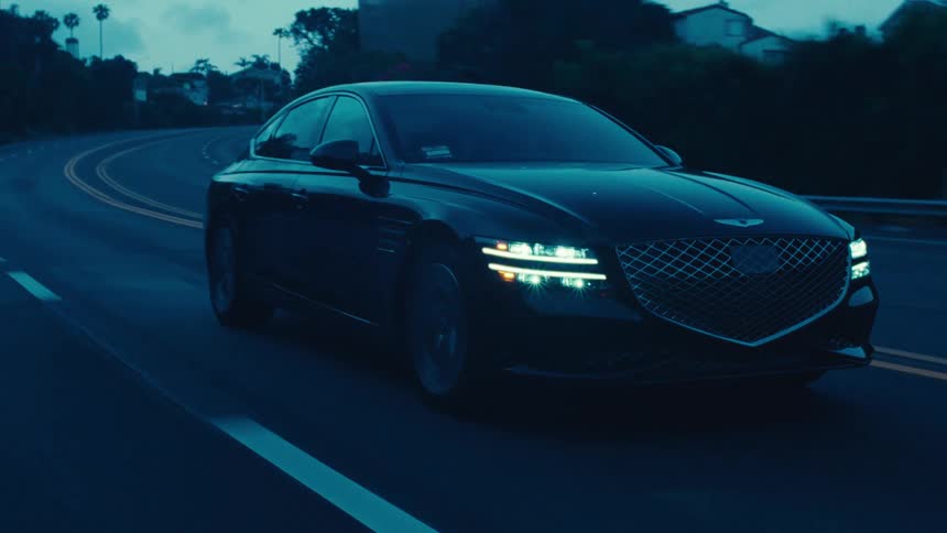 Black sedan car traveling down a highway in the late afternoon