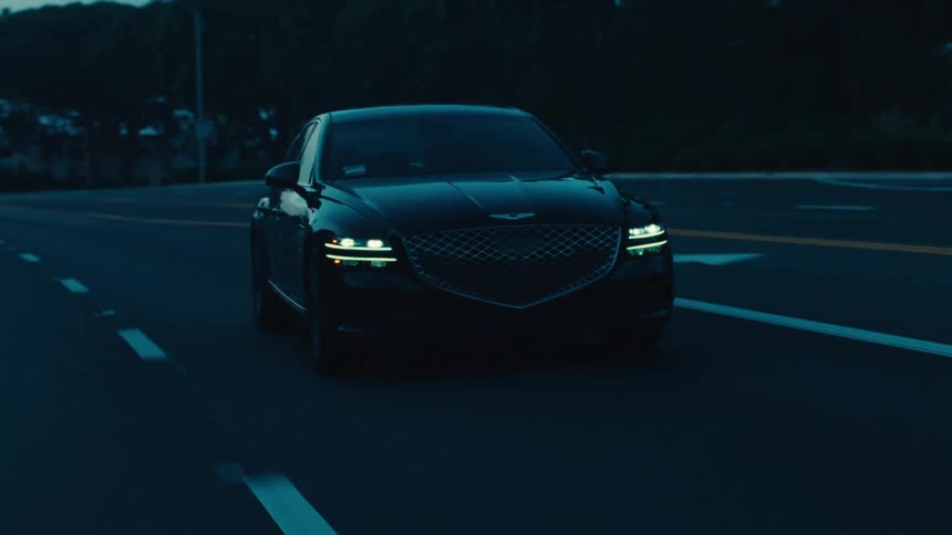 A luxury sedan rolls down a road with other traffic