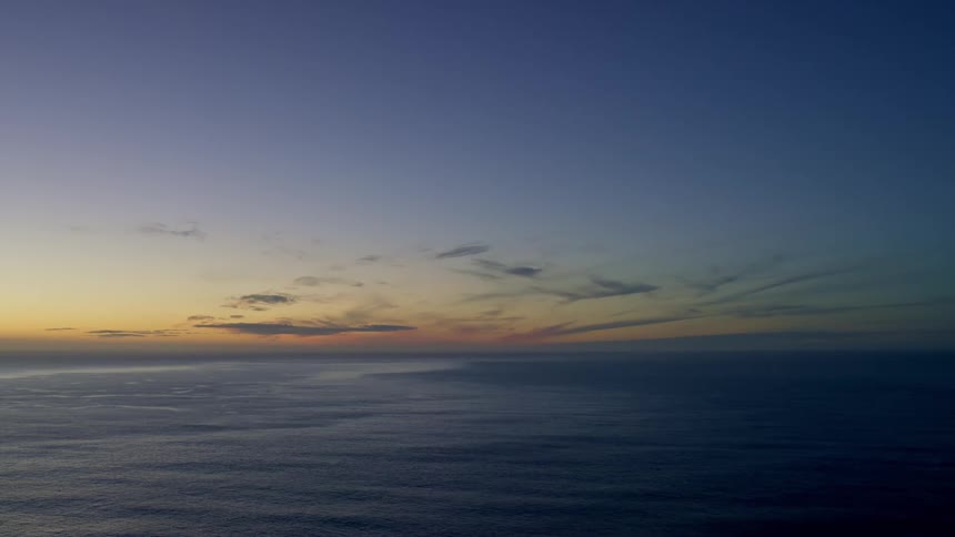 The sun creates an orange glow as it rises over the ocean