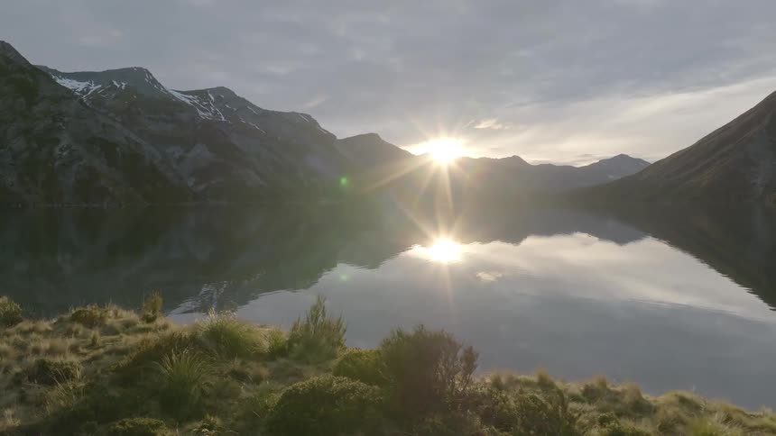 Sunrise on the horizon at a lake surrounded by mountains