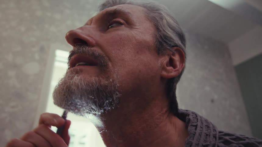 Man shaving with a razor in his bathroom