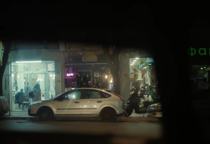 Vehicle traveling along a city street stops for the light at an intersection at night