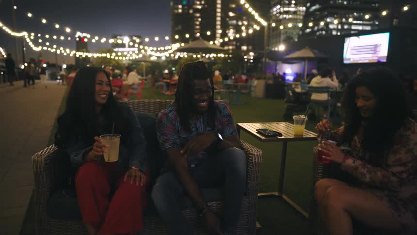 Friends sitting happily with drinks talking in a bright room at night