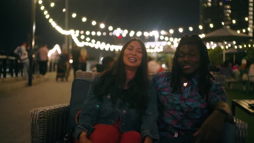 Happy woman and man sitting and talking in a bright room at night