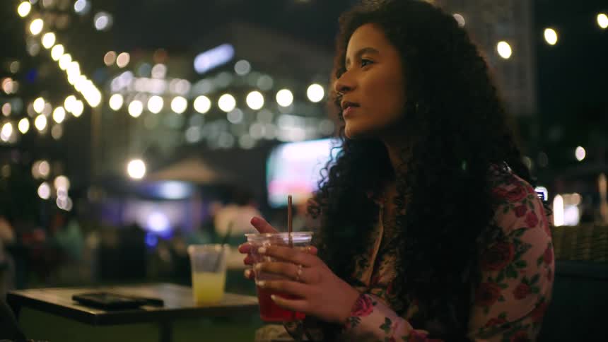 A woman is stirring her drink and talking