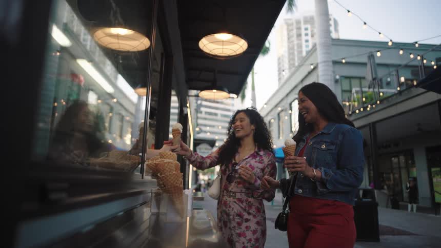 Two friends getting ice cream from a food truck in the city
