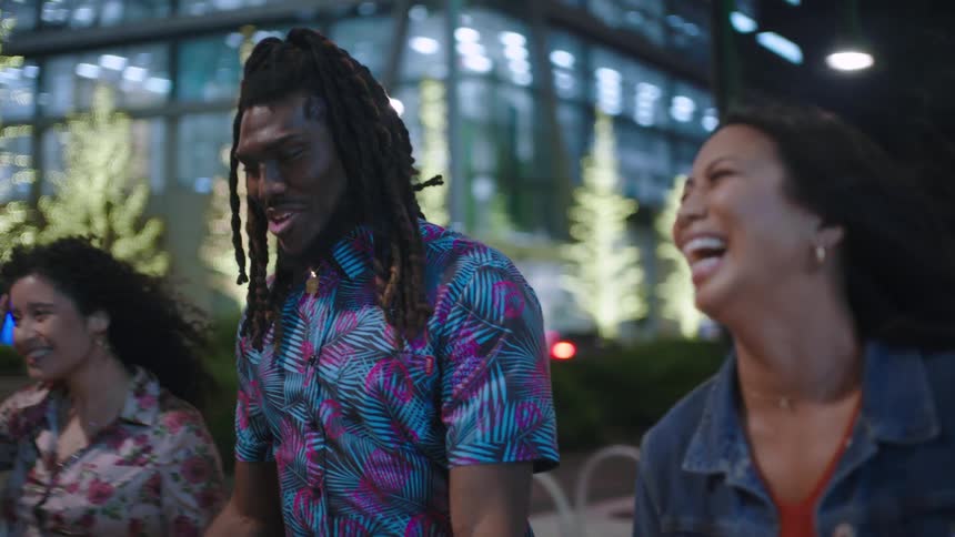 Man with two female friends walking happily through the city at night