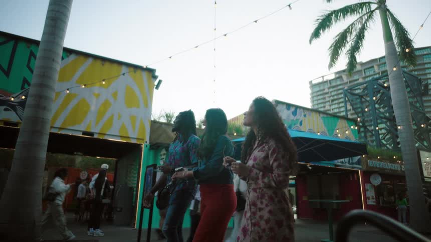 Friends walking through urban streets with shops and bars around