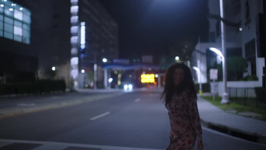 Curly haired woman walking through the city at night