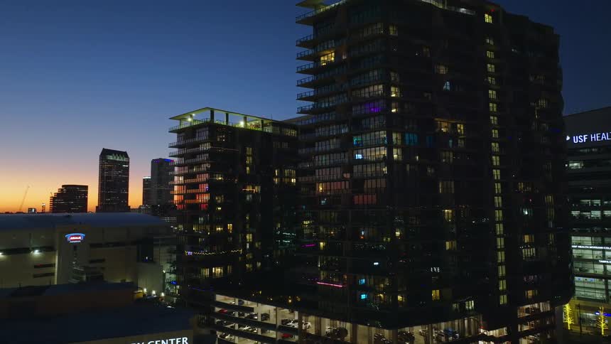 The tall buildings are brightly lit at sunset
