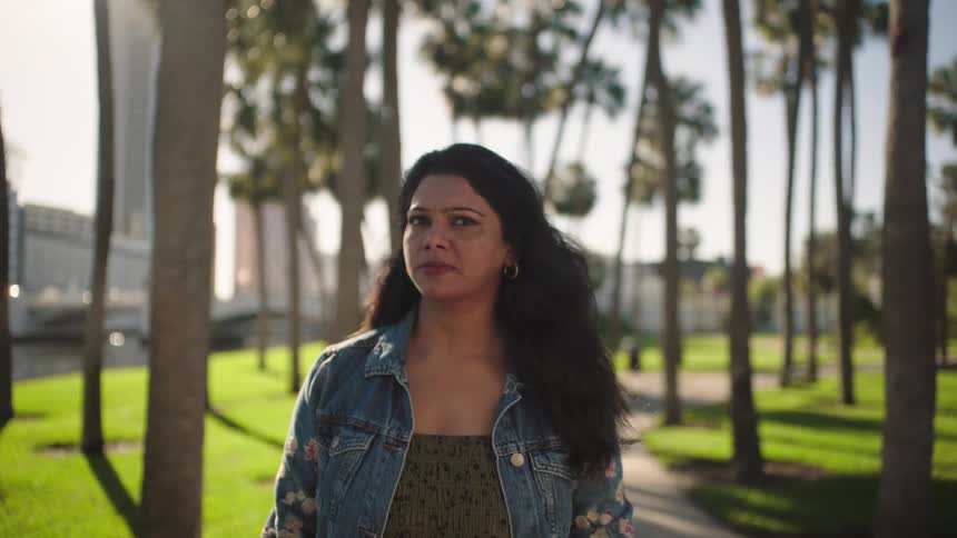 Woman in denim jacket in a setting with palm trees