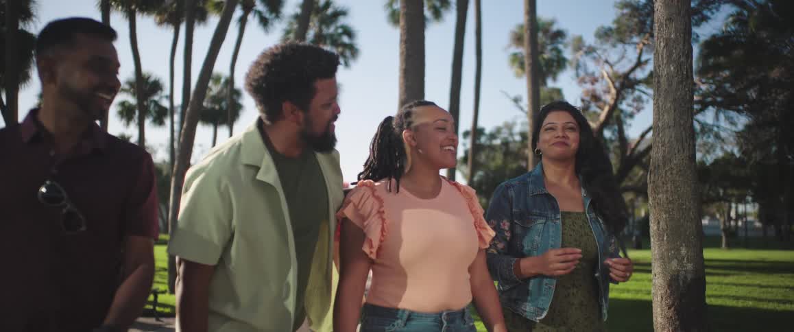 Group of four friends walking through a square with palm trees outdoors