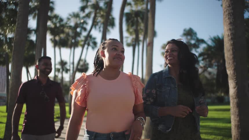 A group of friends smile and chat as they walk in the park