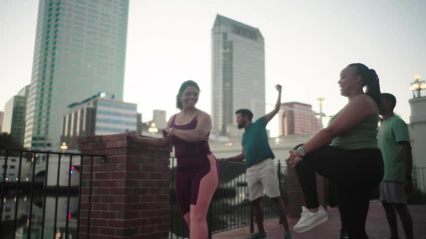 Small group of five people stretching outdoors