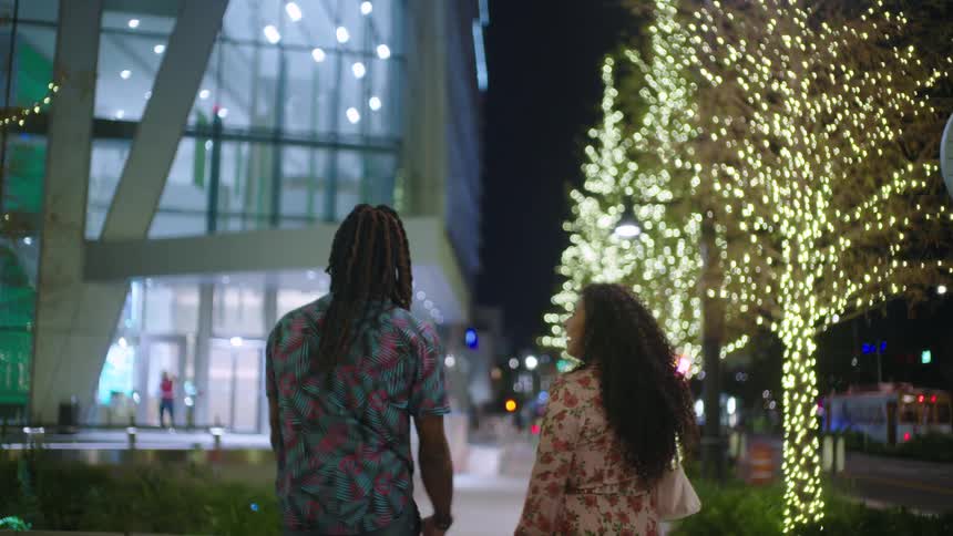 Two friends hugging and walking through the streets of a city at night