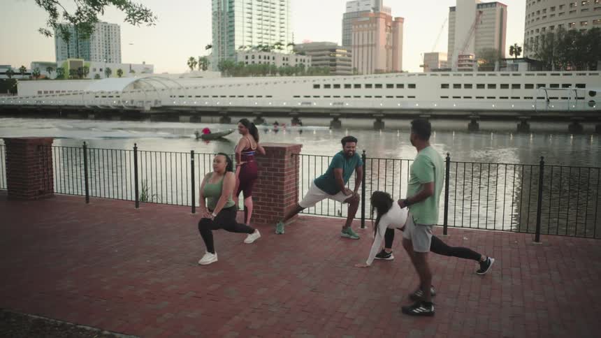 Small group of people on the banks of a sea canal doing body stretches