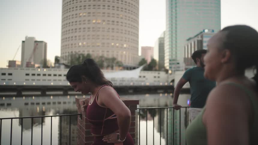 People outdoors by a lake in the city stretching their bodies