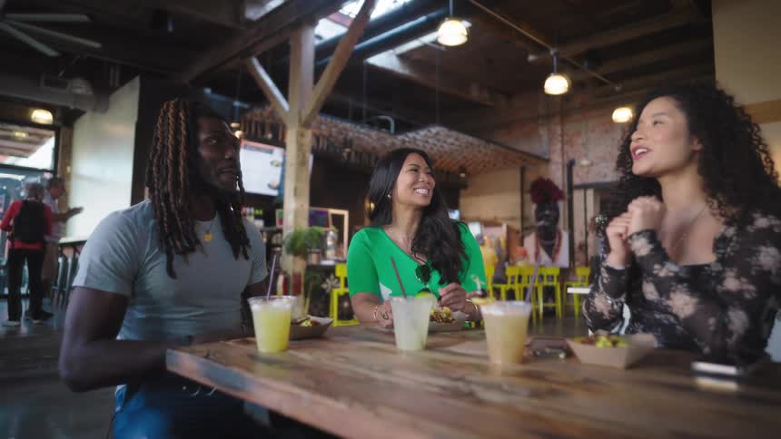 Friends sitting at a bar table with drinks and chatting happily