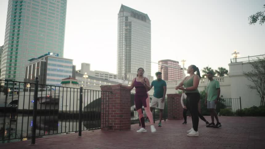 Group of people outdoors stretching their bodies and buildings in the background