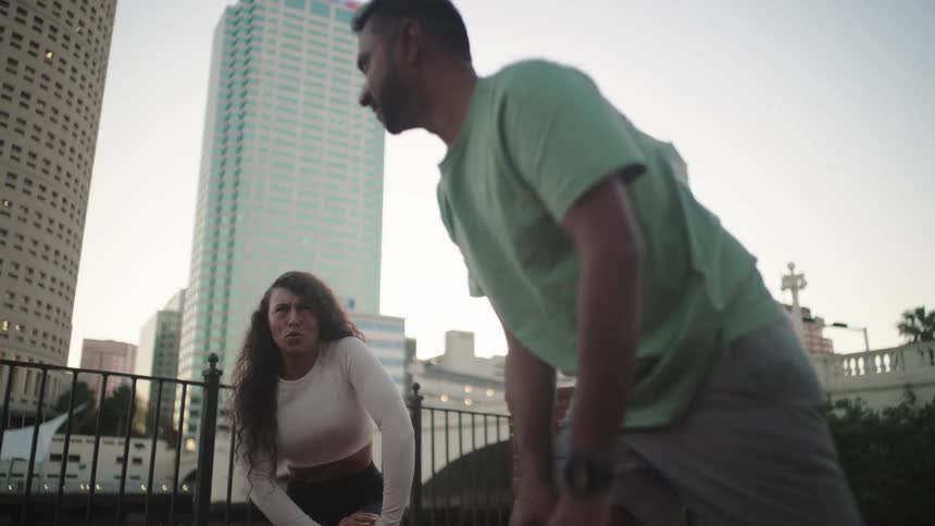 Three people are stretching in a gated area near buildings in the city