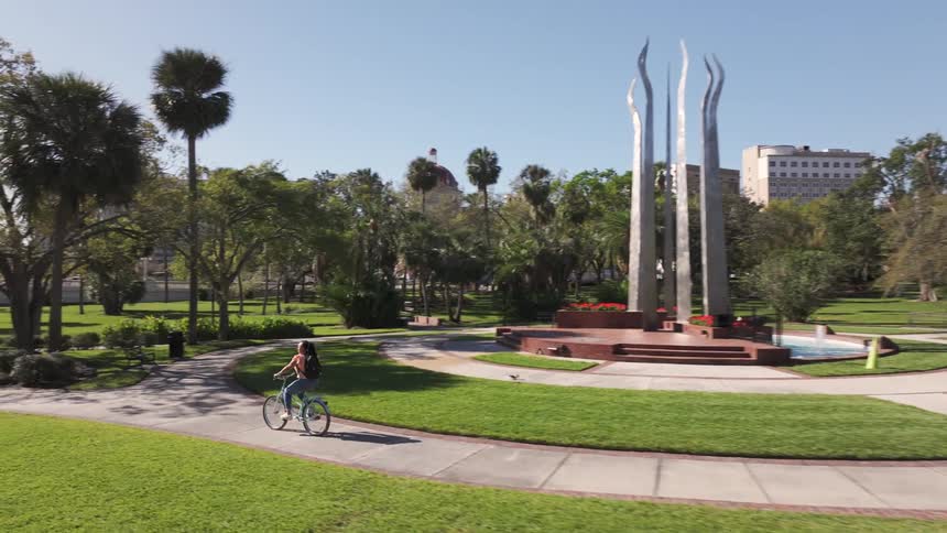 A teenage girl rides her bike around the park of a college campus